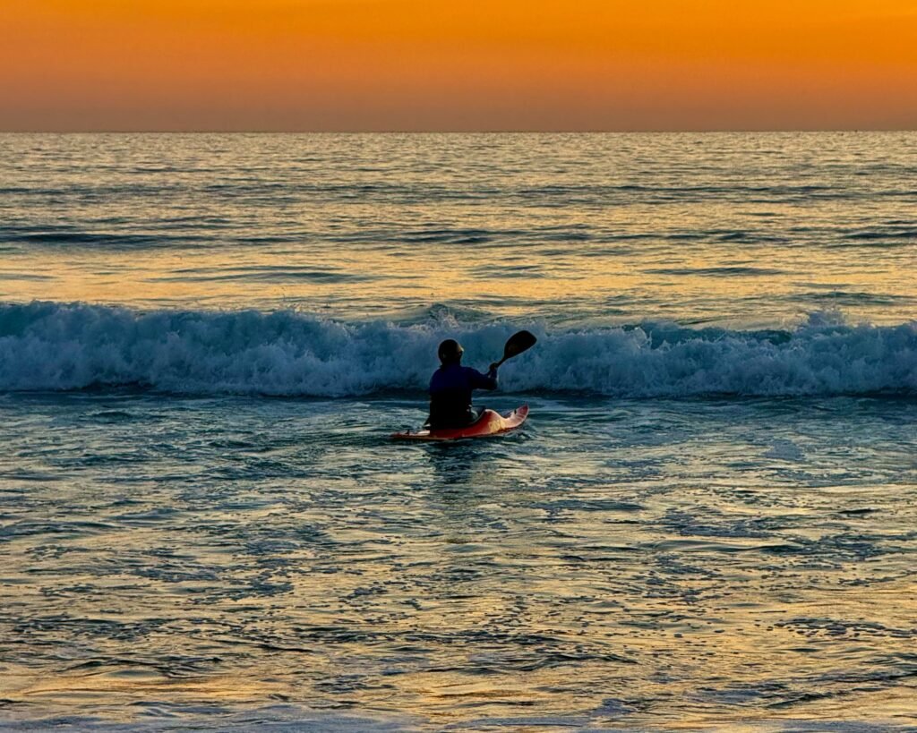 Heading into the waves: kayaker at Freshwater West, Pembrokeshire, Wales