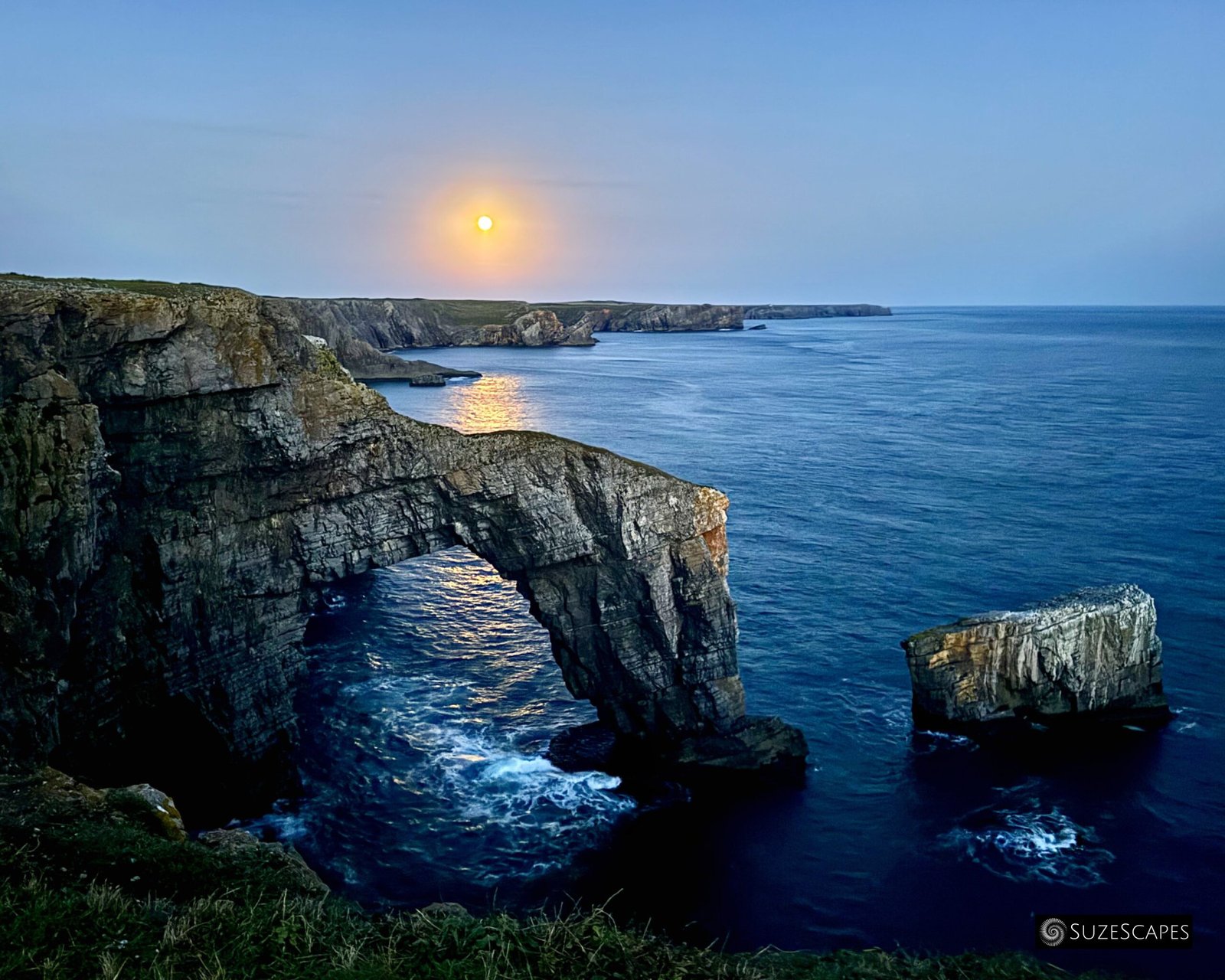 Harvest moon rising at the Green Bridge of Wales, Pembrokeshire, Wales