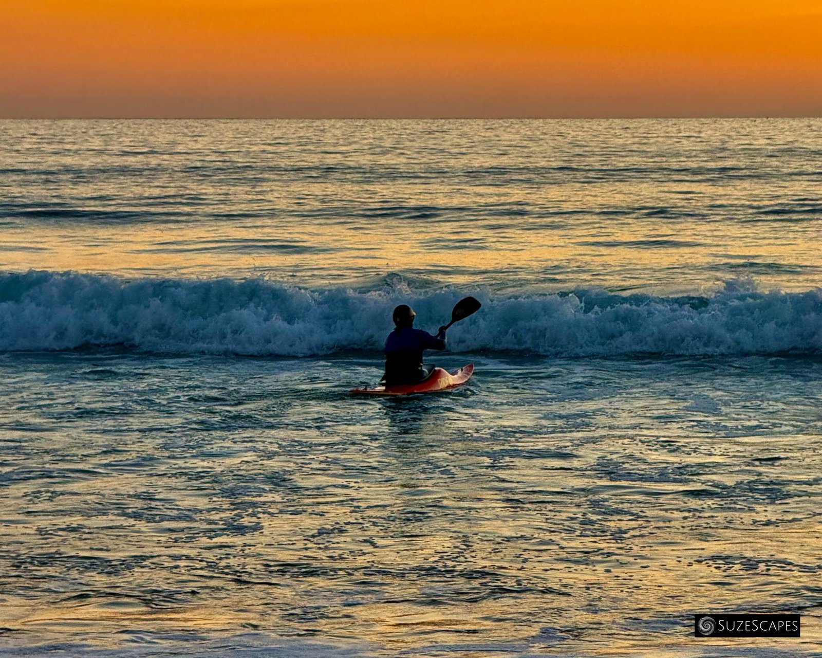Heading into the waves: kayaker at Freshwater West, Pembrokeshire, Wales