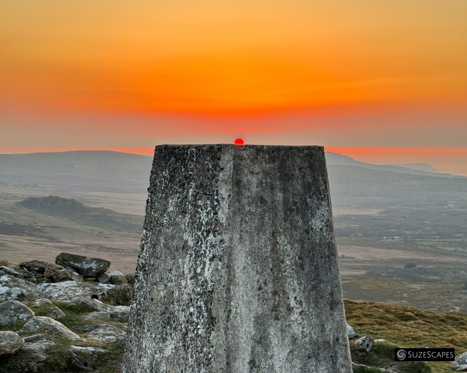 Sun setting on the trig point at Foel Drygarn, Pembrokeshire, Wales